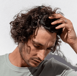 A man looking down touching his hair