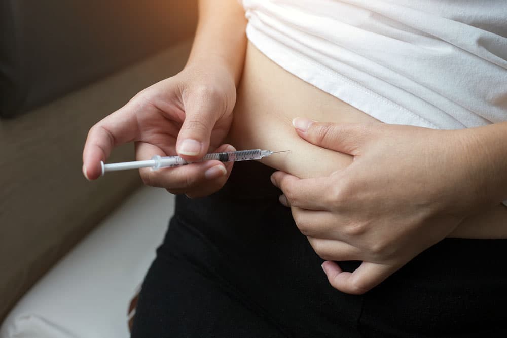 Close-up shot of a person self-injecting with a weight loss drug into their abdomen