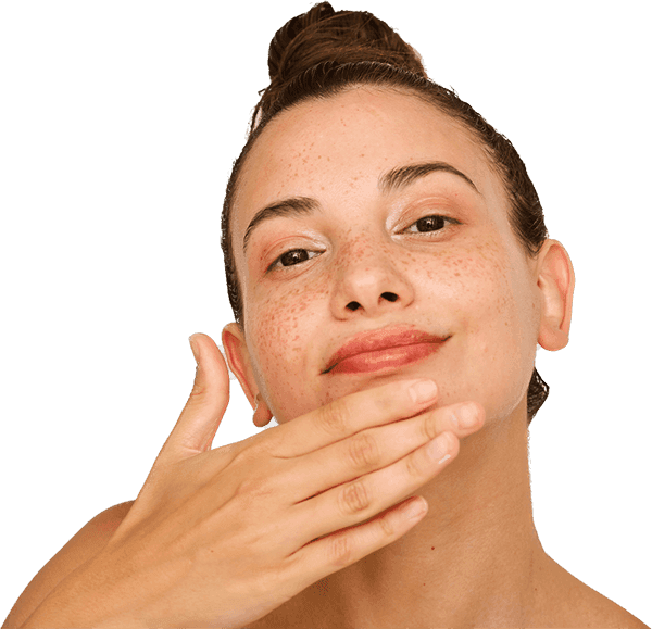 Woman with freckles and hair in the bun touching her chin with her hand and beaming at camera
