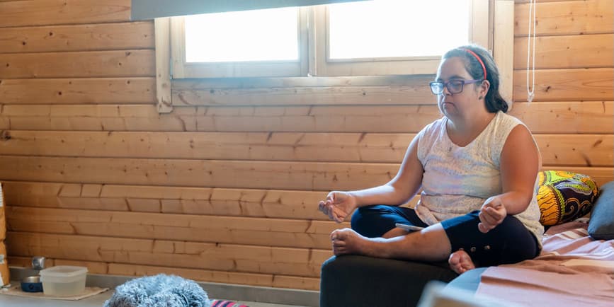 Woman meditating A woman with Down syndrome finds solace in meditation within the confines of her room.