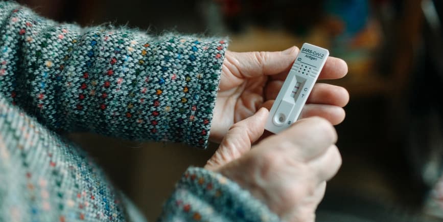 Unrecognizable person's hands checking the positive result of a Covid rapid test at home. She's holding the test in her hands in natural light