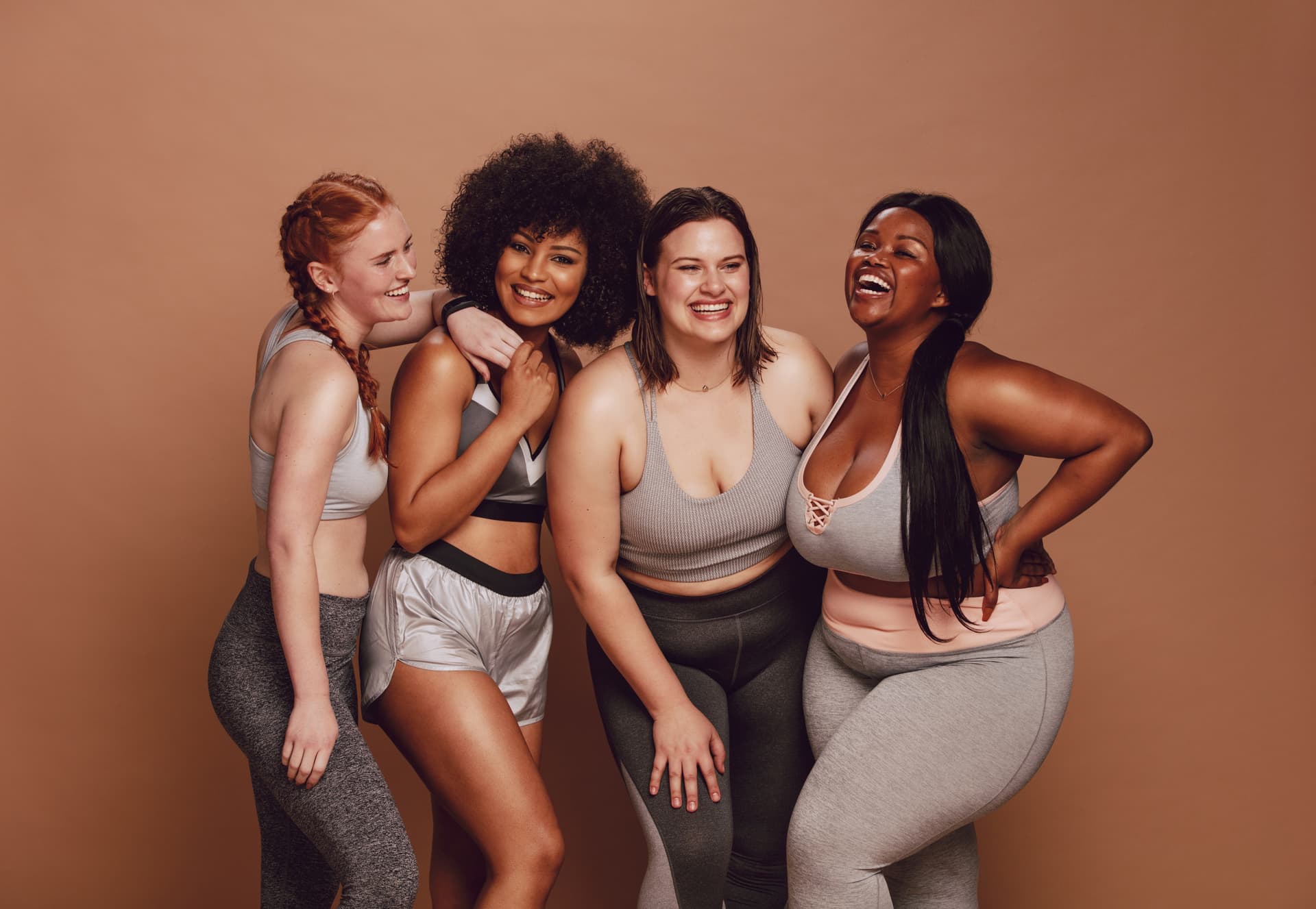 Diverse group of women in matching workout clothes smiling and embracing each other