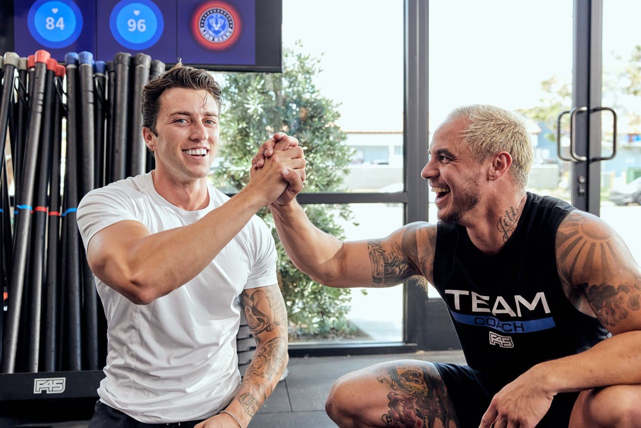 A smiling F45 coach and member high-five in celebration of a successful workout.