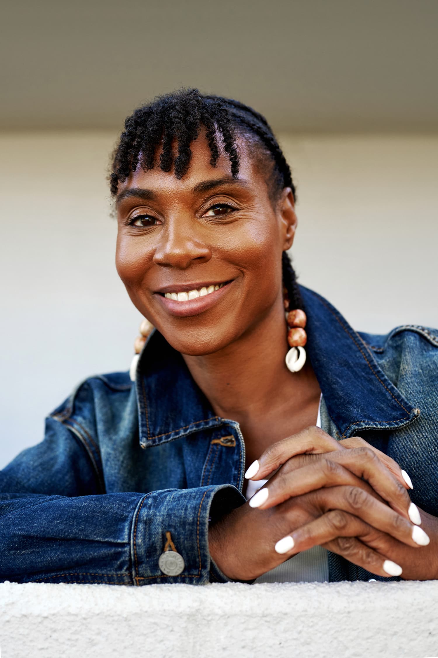 Woman in a denim jacket smiles with quiet confidence and self-assurance, relaxed and at ease