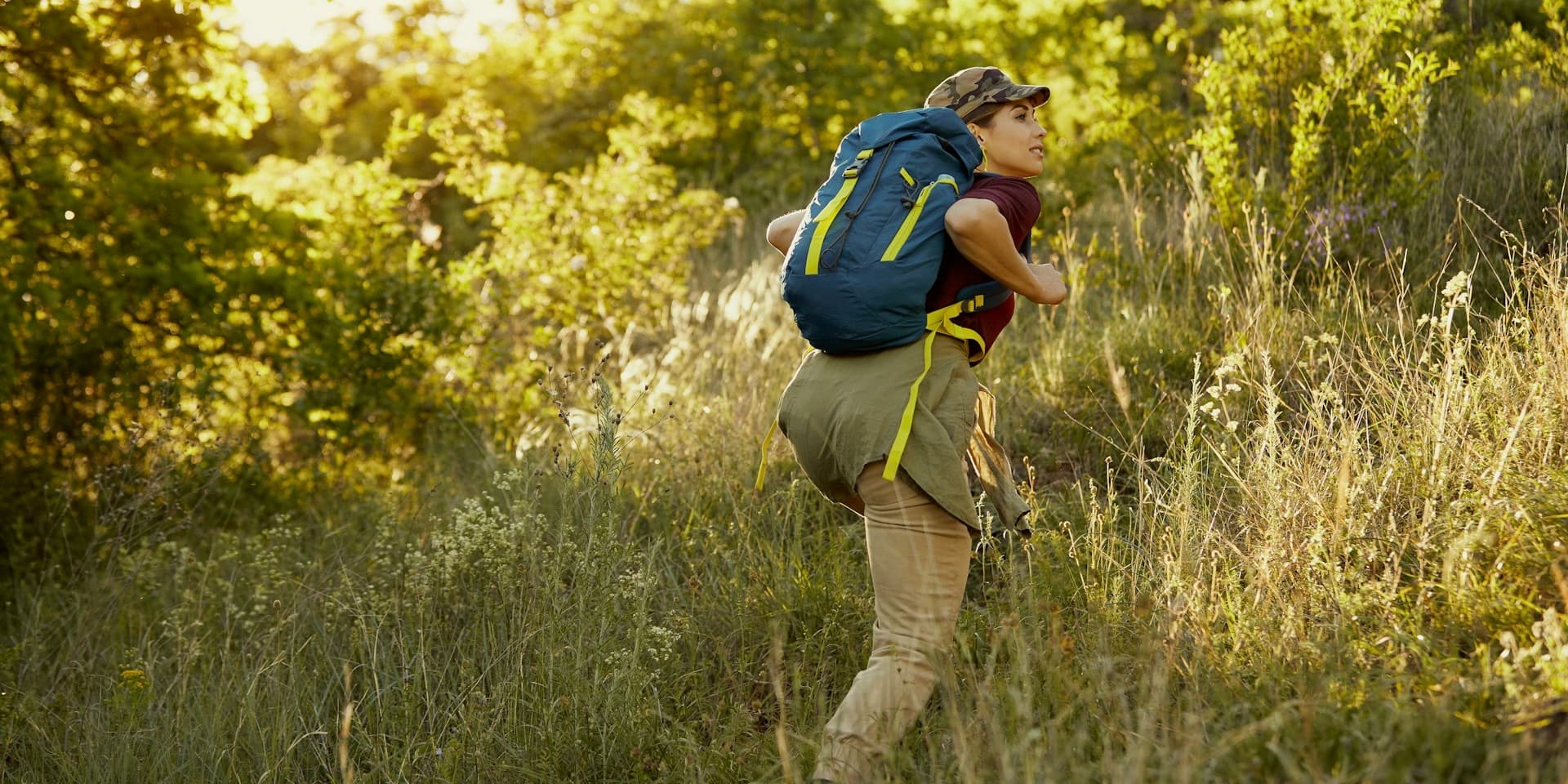 In an article about asthma treatments and symptoms, a young woman smiles as she hikes in the woods on a sunny day.